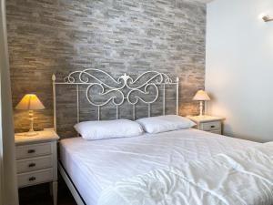 a bedroom with a white bed with a brick wall at Fiocco di Neve Home in Passo del Tonale