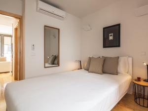 Dormitorio blanco con cama blanca y espejo en InSitu Trindade by Guestify, en Oporto