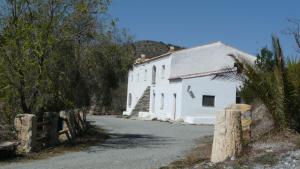 un edificio blanco con una valla al lado de una calle en Cortijo Leontino, en Taberno