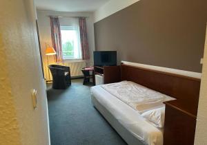 a bedroom with a bed and a desk and a television at Mansfelder Hof in Lutherstadt Eisleben