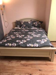 a bedroom with a bed with a black bedspread with flowers at kvartira in Krāslava