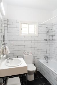 a bathroom with a sink and a toilet and a tub at Kefalos Beach Tourist Village in Paphos City