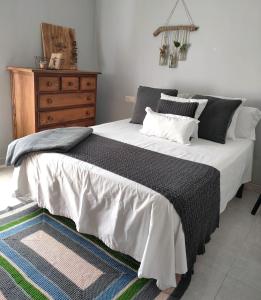 a bed with a black and white blanket and a dresser at Acogedor apartamento en EL VALLE DEL JERTE 1 in Piornal