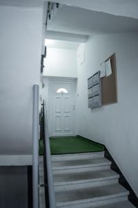 a hallway with stairs and a door with a green carpet at Oskola Luxury Apartment in Szeged