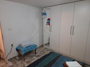 um quarto com armários brancos, um banco e um espelho em Apartman Jaca 