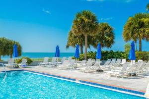 una piscina con sillas, palmeras y el océano en Papaya Place by AvantStay Great Location w Balcony Outdoor Dining Shared Pool Hot Tub, en Key West