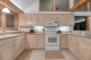 a kitchen with white appliances and wooden cabinets at Bay Cottage by AvantStay Waterfront Pier Pond in Ridge