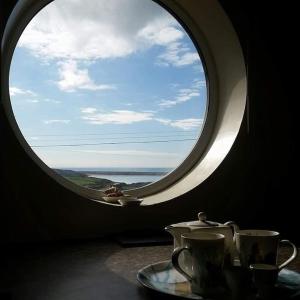 a round window with a table with cups and a plate at Seaview Self-Catering in Weymouth
