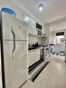 a kitchen with a white refrigerator in a room at champs frente mar ao sol in Balneário Camboriú