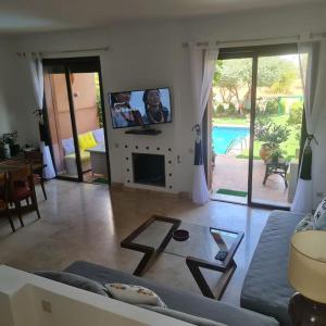 een woonkamer met een bank en een tv bij TOP Villa Pavillon dans Golf à 20 min de Marrakech in Sraghna