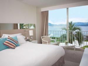 a hotel room with a large bed and a large window at Sofitel Golfe d'Ajaccio Thalassa Sea & Spa in Ajaccio