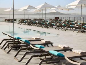 a row of lounge chairs and a swimming pool at Sofitel Golfe d'Ajaccio Thalassa Sea & Spa in Ajaccio