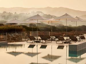 a group of chairs and umbrellas next to a pool at Sofitel Golfe d'Ajaccio Thalassa Sea & Spa in Ajaccio