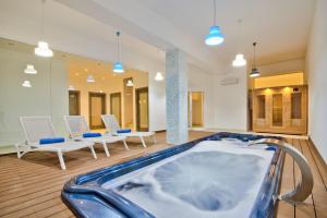 eine Whirlpool-Badewanne in einem Zimmer mit weißen Stühlen in der Unterkunft Villa Ida - Indoor Heated Pool, Sauna, Games Room and Gym in Mellieħa
