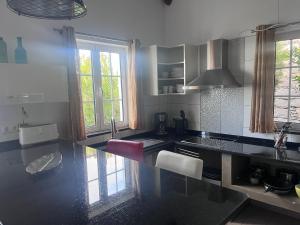 a kitchen with a black counter top and two windows at Lucky Lemons - Boutique Houses Madeira - 2 in Estreito da Calheta
