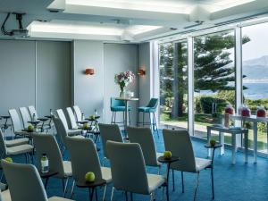 a waiting room with chairs and tables and windows at Sofitel Golfe d'Ajaccio Thalassa Sea & Spa in Ajaccio