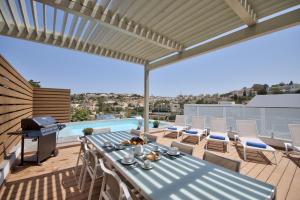 eine Terrasse mit einem Tisch, Stühlen und einem Grill in der Unterkunft Villa Ida - Indoor Heated Pool, Sauna, Games Room and Gym in Mellieħa