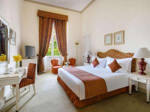 Cette chambre comprend un grand lit blanc et un bureau. dans l'établissement Sofitel Winter Palace Luxor, à Louxor