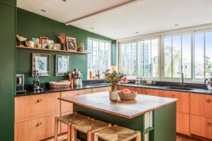 uma cozinha com paredes verdes e uma mesa e cadeiras em Appartement Borghese - Welkeys em Boulogne-Billancourt