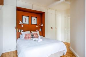 een slaapkamer met een wit bed met een oranje hoofdeinde bij Appartement Borghese - Welkeys in Boulogne-Billancourt