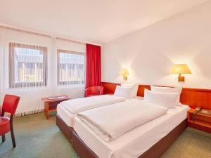 Cette chambre comprend un grand lit et des rideaux rouges. dans l'établissement Mercure Hotel Bad Duerkheim An Den Salinen, à Bad Dürkheim