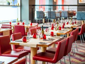 un restaurante con mesas de madera y sillas rojas en Novotel Glasgow Centre en Glasgow