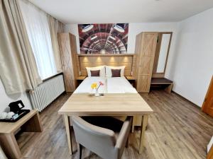 ein kleines Zimmer mit einem Bett und einem Holztisch in der Unterkunft Hotel Rheintal in Kappel-Grafenhausen