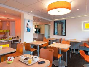 un restaurante con mesas y sillas y una cafetería en Ibis budget Wien Messe en Viena