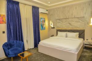 een slaapkamer met een bed en een blauwe stoel bij SS3 Jabi Hotel in Abuja