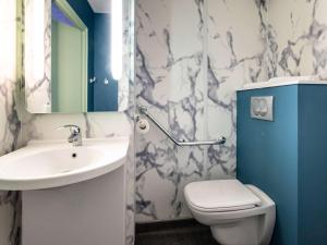 La salle de bains est pourvue d'un lavabo, de toilettes et d'un miroir. dans l'établissement Ibis budget Saint-Étienne stade, à Saint-Étienne