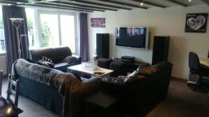 sala de estar con sofás y TV de pantalla plana. en Bed & Kitchen Den Oever, en Den Oever