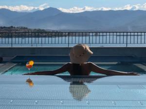 ibis Styles Ajaccio Napoleon في أجاكسيو: امرأة جالسة في حمام سباحة مع كوب من النبيذ