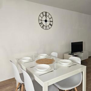 une table à manger blanche avec des chaises blanches et une horloge dans l'établissement Emplacement Idéal : Appartement 2 Chambres en Plein Cœur d'Orange, à Orange