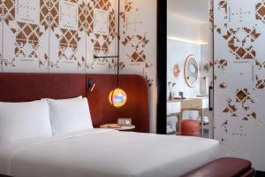 a bedroom with a large white bed and a mirror at Andaz Doha, A Concept by Hyatt in Doha