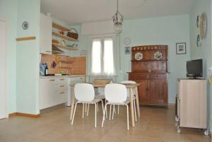 una cucina con tavolo e sedie bianche di Villa Margherita Bilocale - Taunus Vacanze a Numana