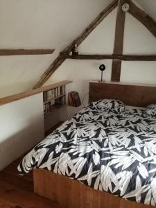 een slaapkamer met een bed met een zwart-wit dekbed bij La Canardière in Pendé