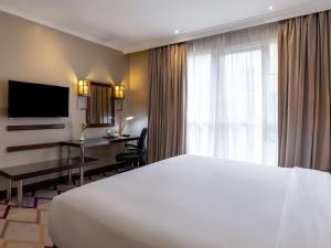 a hotel room with a white bed and a desk at Mercure Nairobi Upper Hill in Nairobi