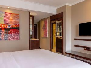 um quarto com uma cama e uma televisão de ecrã plano em Mercure Nairobi Upper Hill em Nairobi