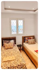 two beds in a room with two windows at *APPARTEMENT NEUF AVEC TERRASSE À LA MARSA*** in La Marsa