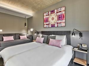 a bedroom with a large white bed and a couch at Number 11 St Julian's Malta - Handwritten Collection in St. Julianʼs