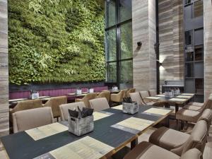 a restaurant with tables and chairs and a green wall at Number 11 St Julian's Malta - Handwritten Collection in St. Julianʼs