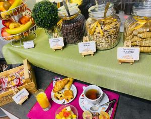 a table topped with bowls of food and cups of tea at Hotel & Spa Gil de France Cap d'Agde in Cap d'Agde