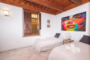 two beds in a room with a painting on the wall at Alh Patio Apartamentos in Granada