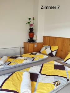twee bedden in een kamer met geel en wit bij Zimmer in Ein Haus mit Waschmaschine in Mönchengladbach