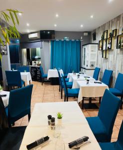 un restaurante con mesas blancas y sillas azules en Hotel & Spa Gil de France Cap d'Agde en Cap d'Agde