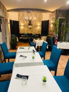 a restaurant with white tables and blue chairs at Hotel & Spa Gil de France Cap d'Agde in Cap d'Agde