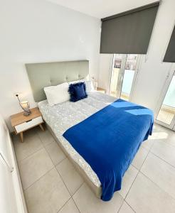 a bedroom with a large bed with blue sheets at Cosmopolitan by Lovely Property in Corralejo