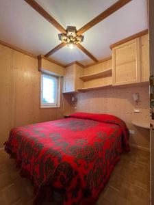a bedroom with a red bed in a room at Appartamento con vista sulle Pale di San Martino in San Martino di Castrozza