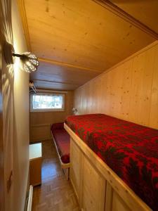 a small bedroom with a red bed in a cabin at Appartamento con vista sulle Pale di San Martino in San Martino di Castrozza