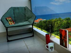 einen Stuhl auf dem Balkon mit einer Kaffeetasse in der Unterkunft Mi Amor Luxury Island Apartment - 3 minutes to the beach in Phu Quoc